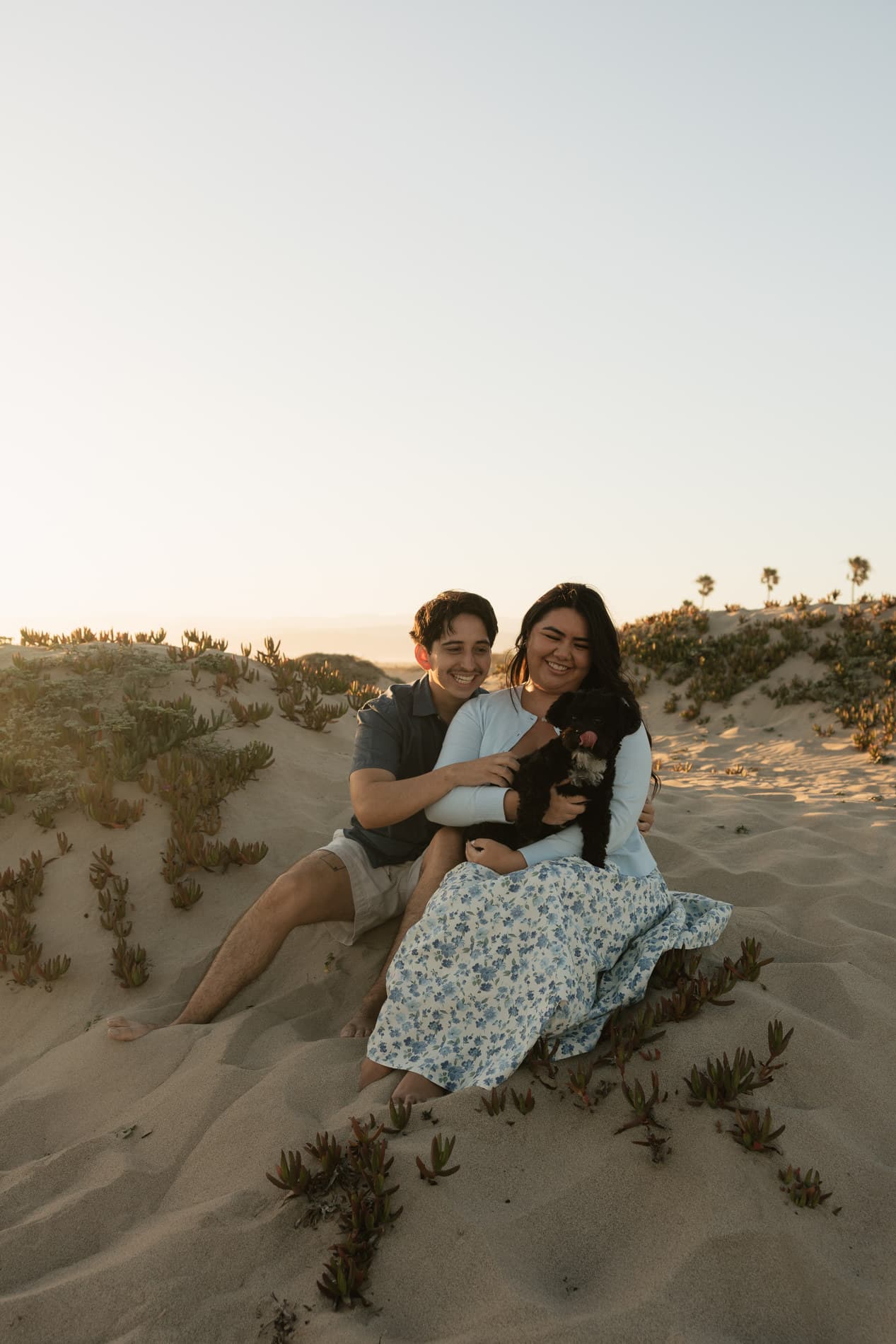 Nicolas and Alexandra sitting in the dunes with their dog